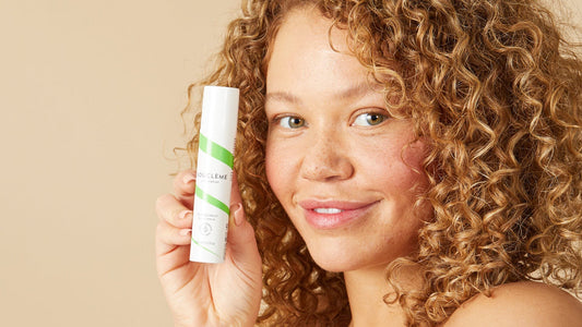 woman with curly hair holding Bouclème's dry scalp serum
