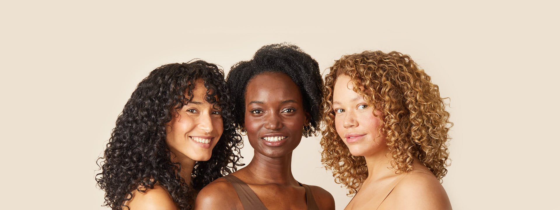 Three smiling women with curly hair posing for the camera