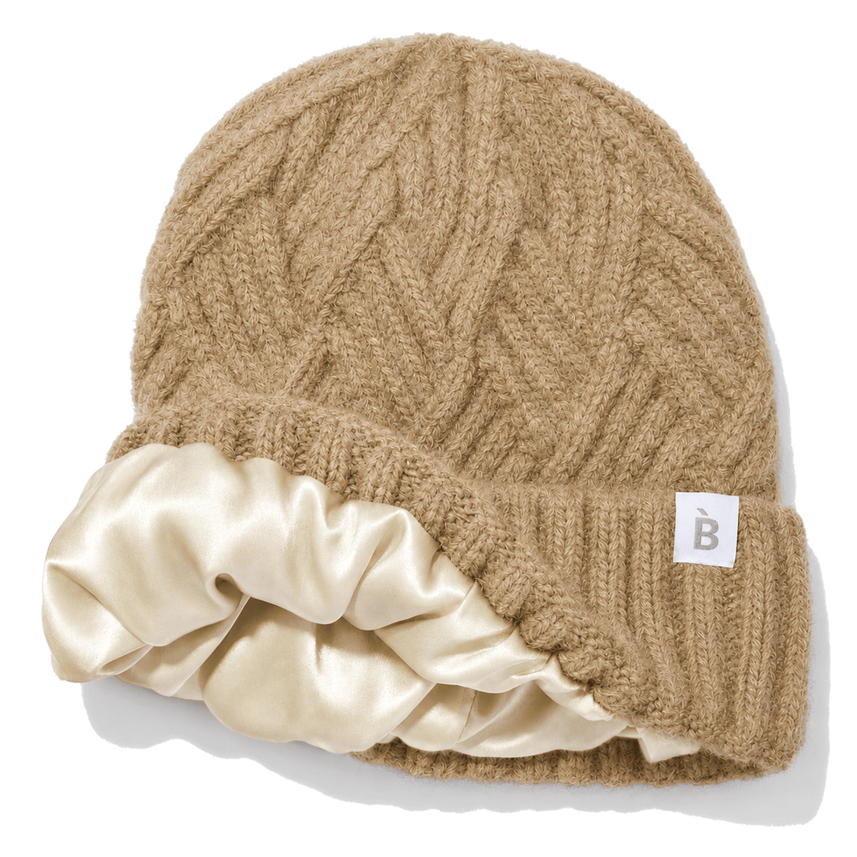 A camel cable-knit beanie hat with a wide cream silk inner lining and a small white square tag on the side.