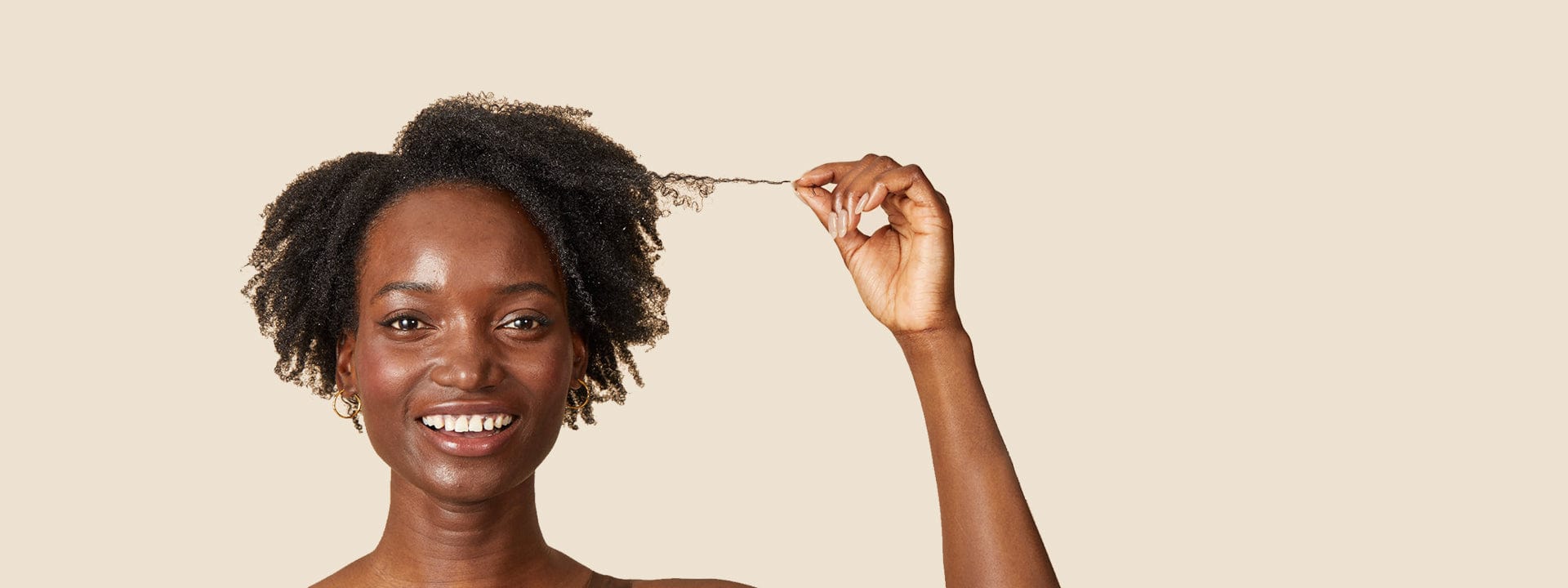 smiling, black woman holding out a few strands of her black, coily hair