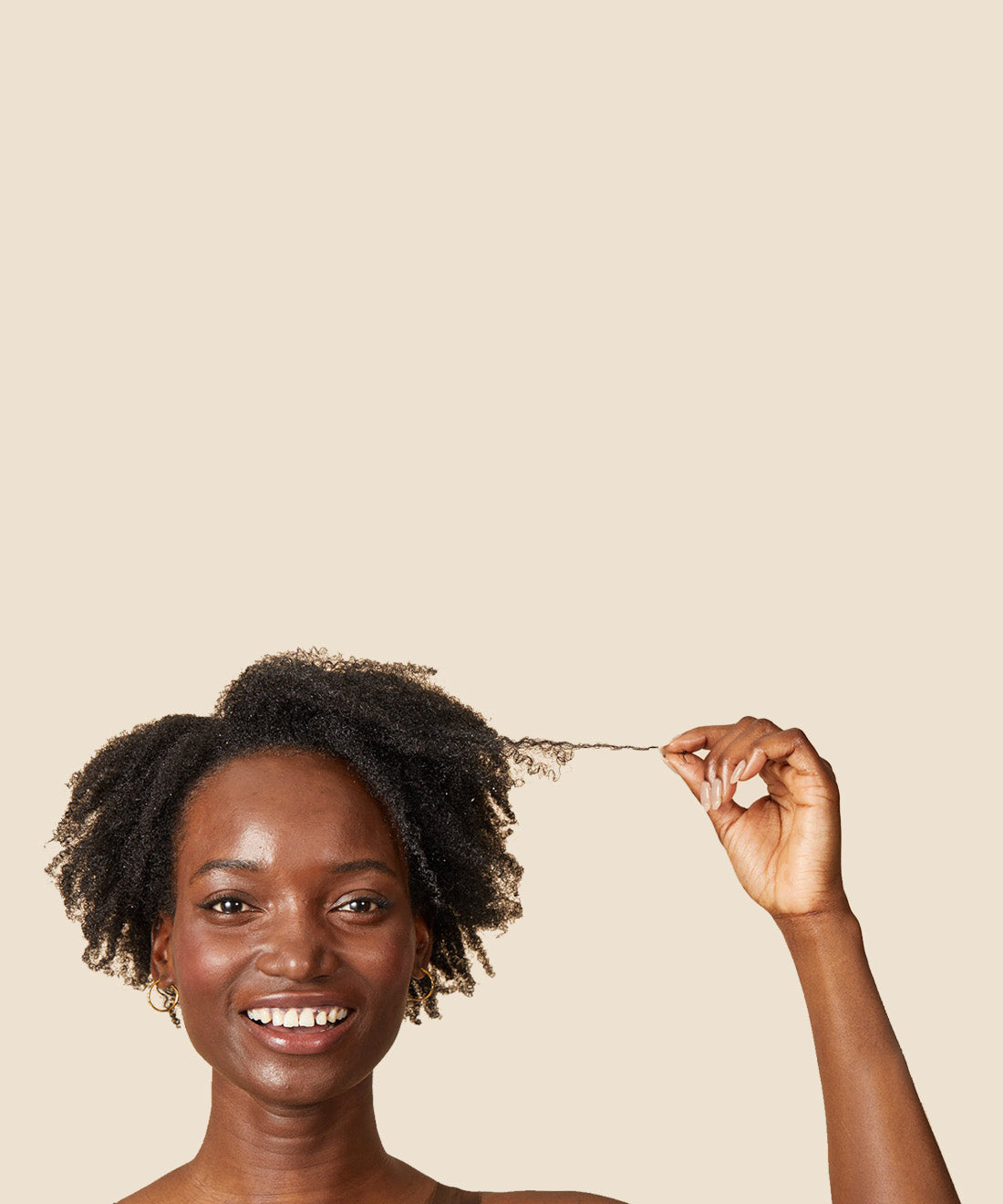 smiling, black woman holding out a few strands of her black, coily hair