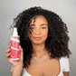 Model applying flexible hold hair spray on dry curly hair to fix the style in place
