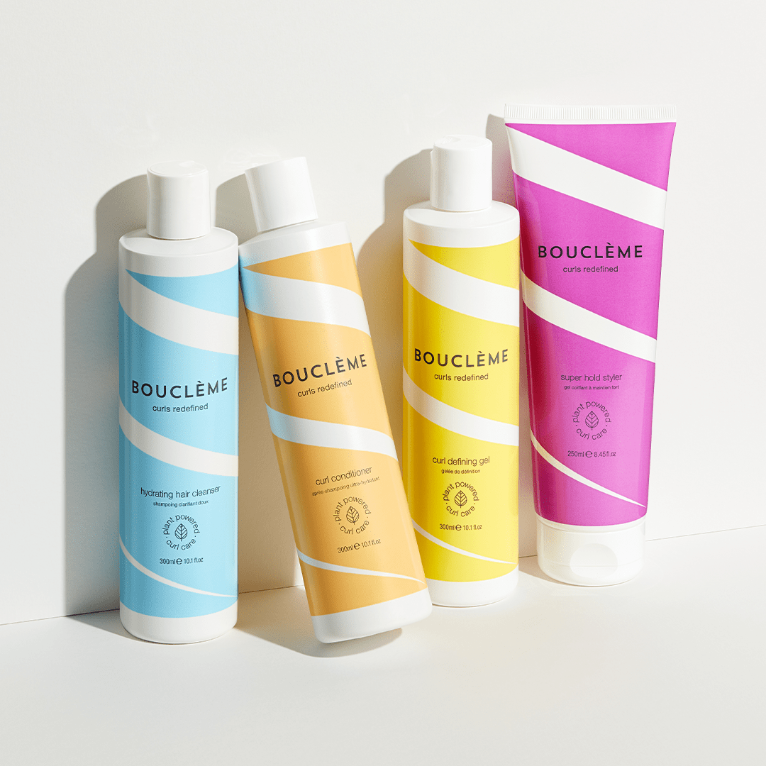 four bottles of Bouclème's products for curly hair propped up against a wall