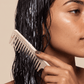 curly hair person applying Strength and Repair Duo to hair